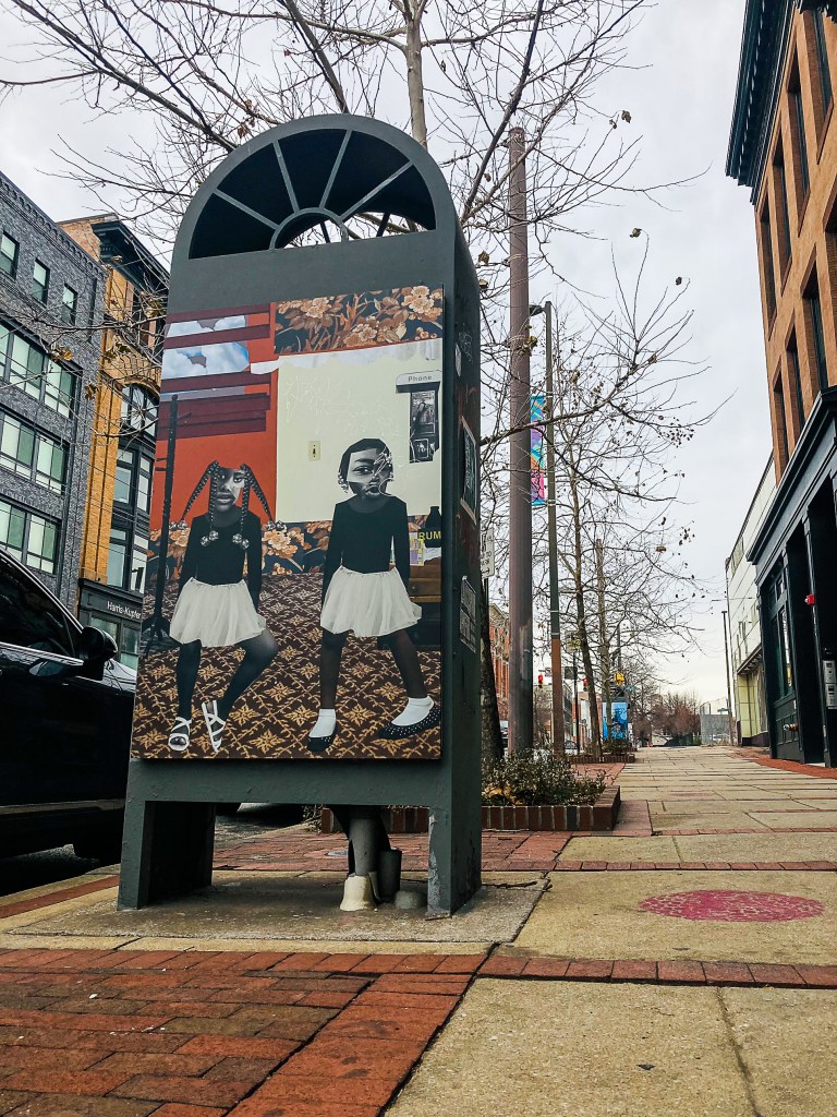 A collage artwork on display on a kiosk outside of Current Space on North Howard Street.