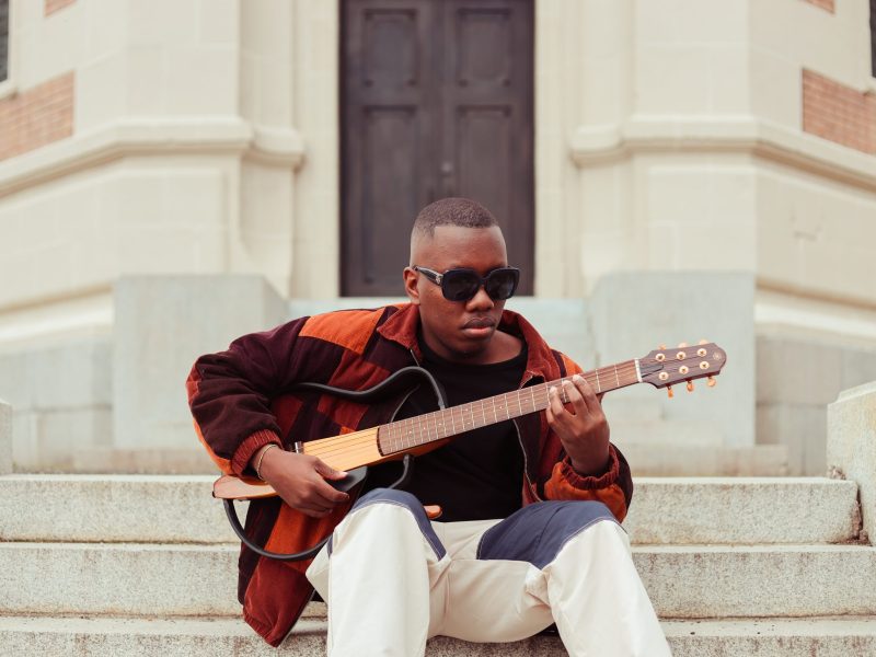 color photograph of a man with brown skin playing a guitar.