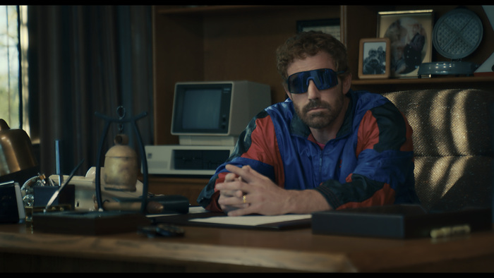 Photo of Ben Affleck wearing a windbreaker and sunglasses. 
