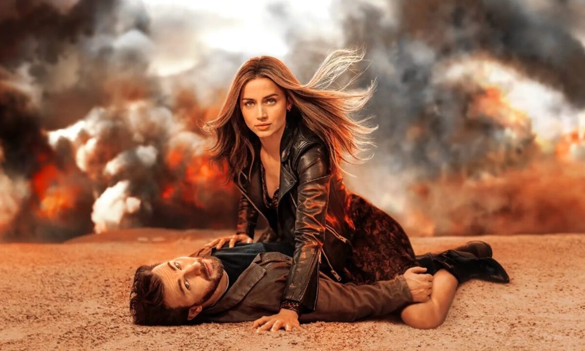 A still from a film where two characters look at the camera, there is smoke in the background.