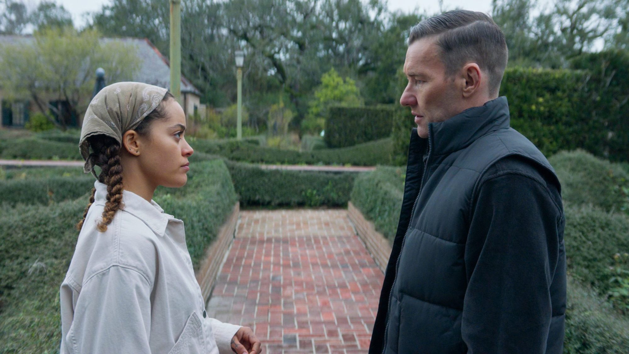 Quintessa Swindell as Maya Core and Joel Edgerton as Narvel Roth in Paul Schrader’s “Master Gardener.” (2022). The figures, one male and one female are looking at each other in a garden.