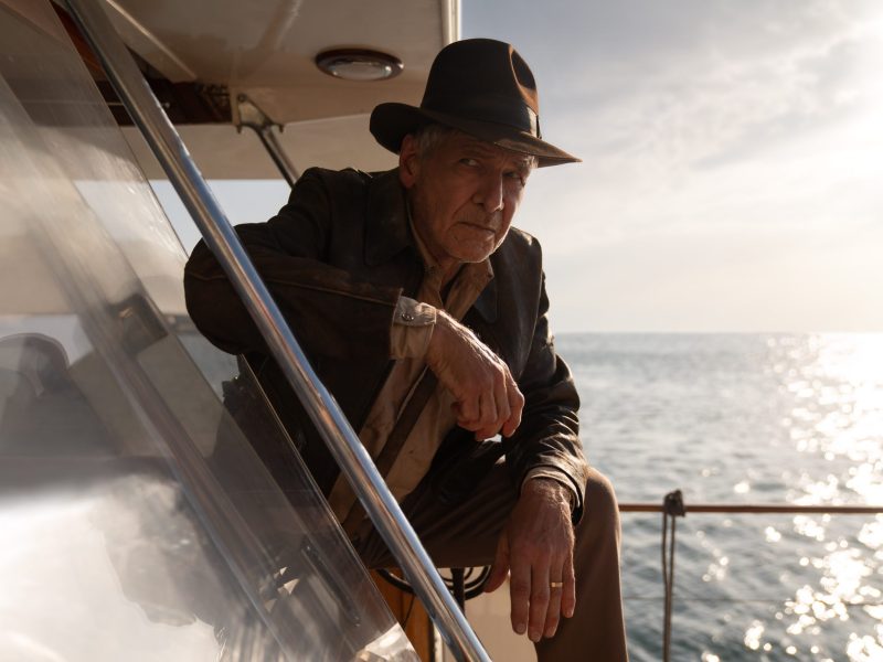 Harrison Ford as Indiana Jones. Film still with the actor wearing a hat looking out at the water.