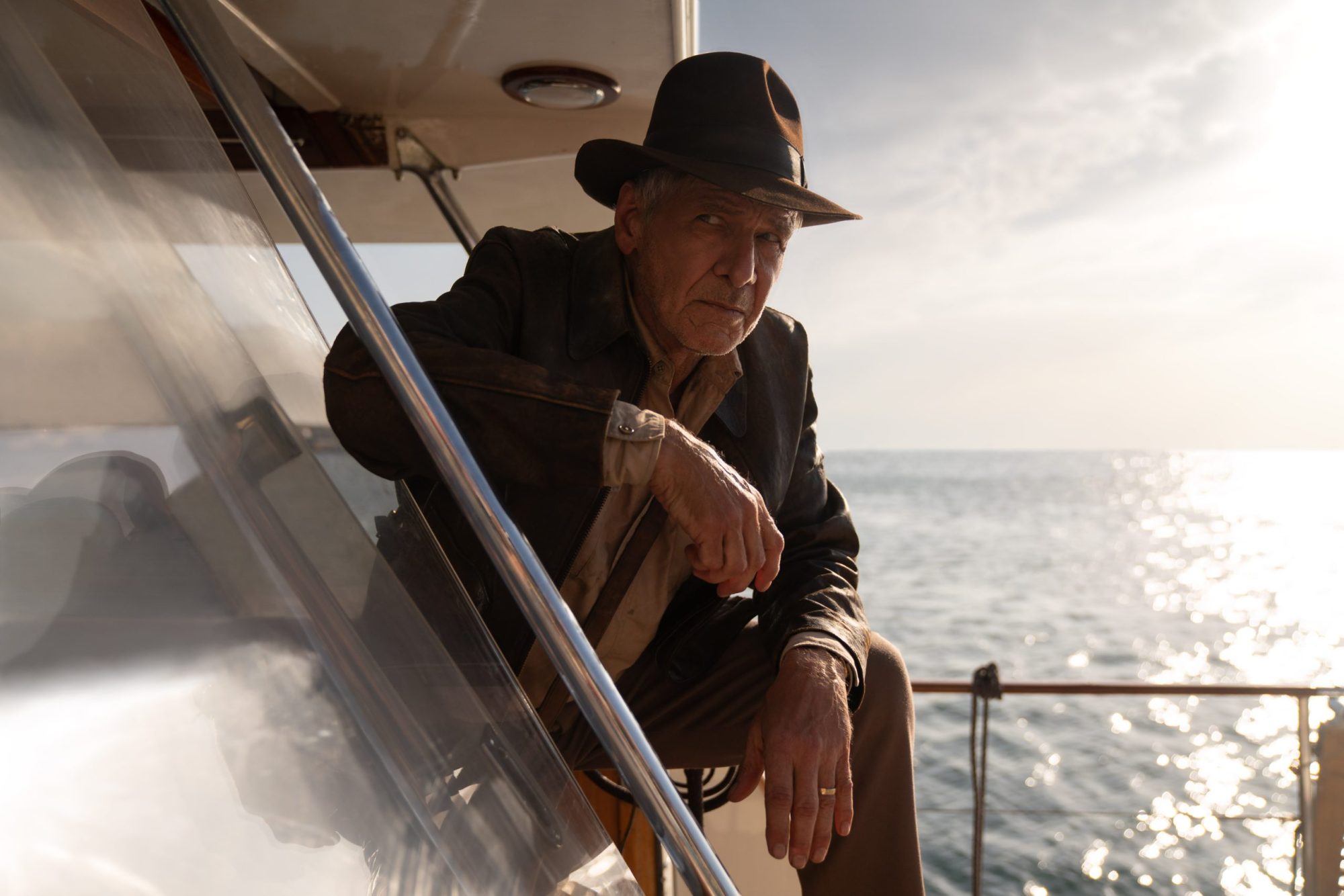 Harrison Ford as Indiana Jones. Film still with the actor wearing a hat looking out at the water.