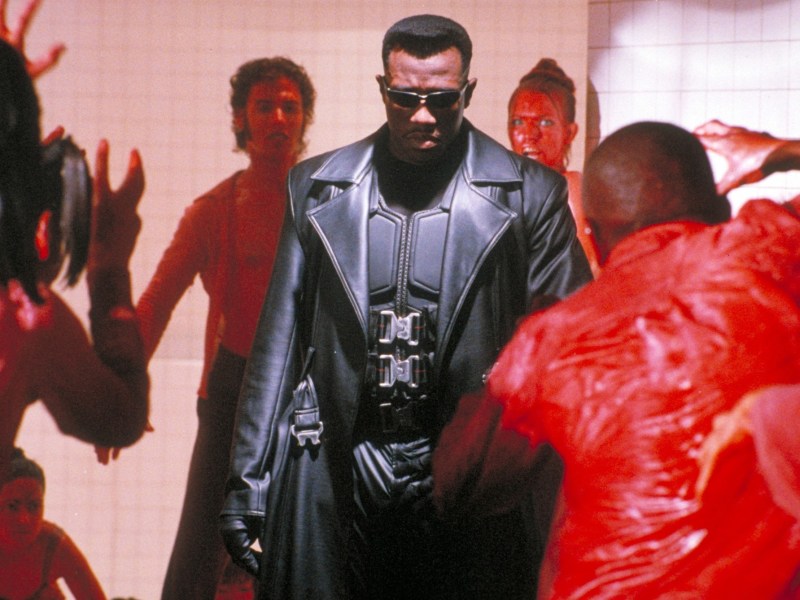 Still from the movie Blade, a man in a black leather trench coat is in the center of the photo.