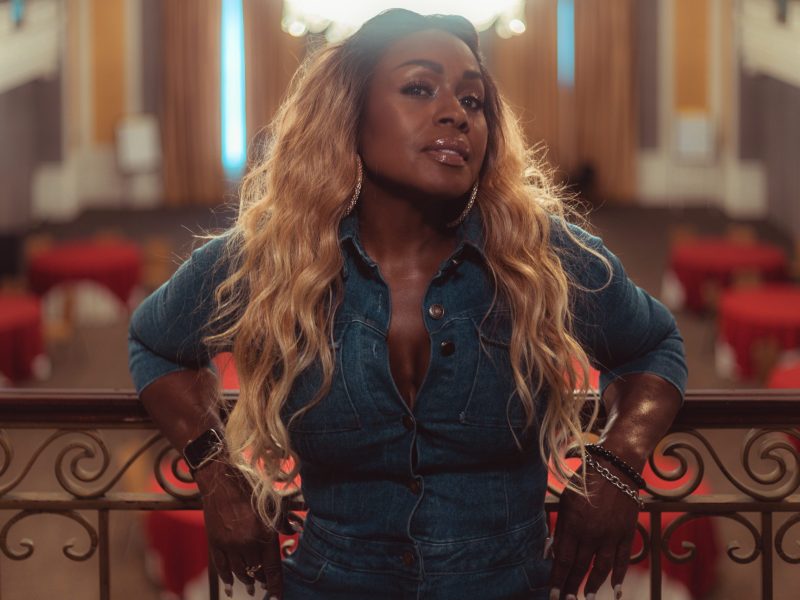 A woman with brown skin and blonde hair poses.