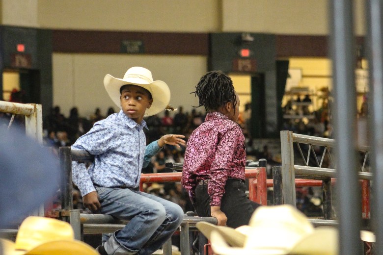 Two young participants in the BPIR. One wears a blue shirt with a tan cowboy hat, the other has her hair in braids and wears a pink shirt.