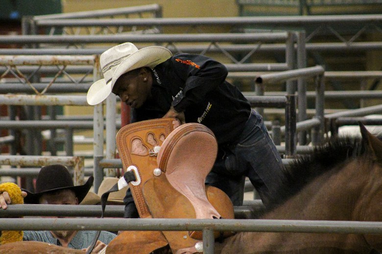 A Black cowboy mounts his to prepare to enter the arena at the Bill Pickett invitational rodeo.