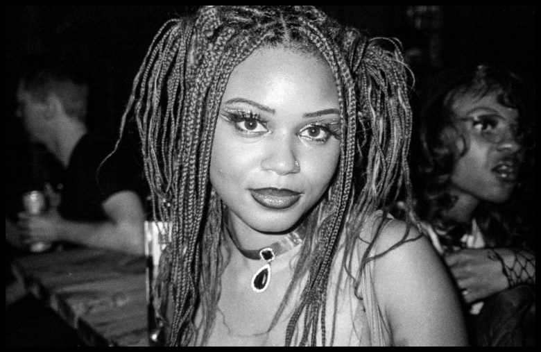 A person smiles in a black and white photograph.