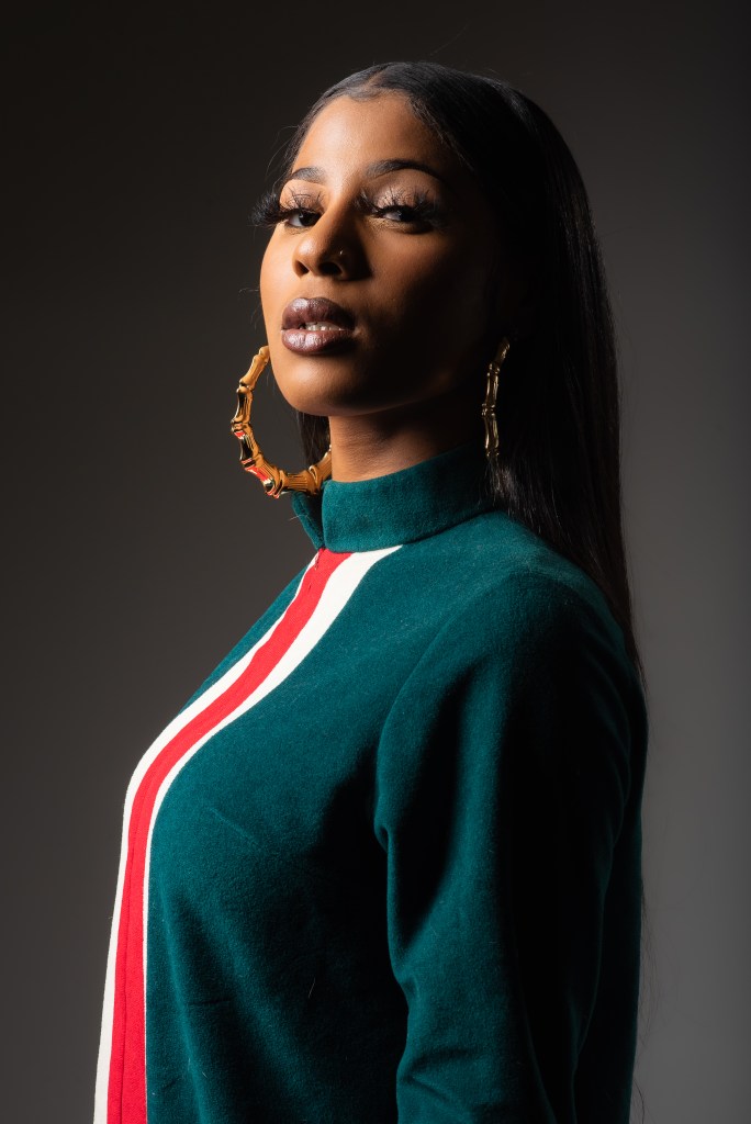 A woman with brown skin looks at the camera. 