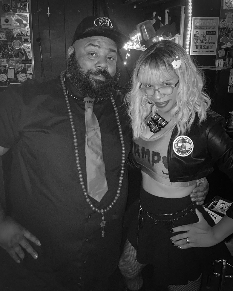 Two people with brown skin pose for a photograph.