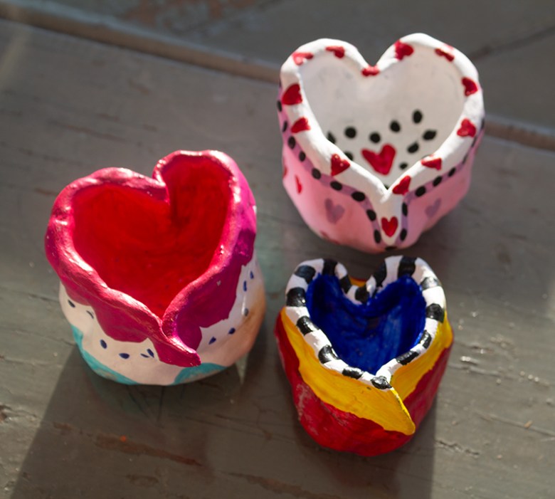 A color photograph of three multicolored clay hearts.