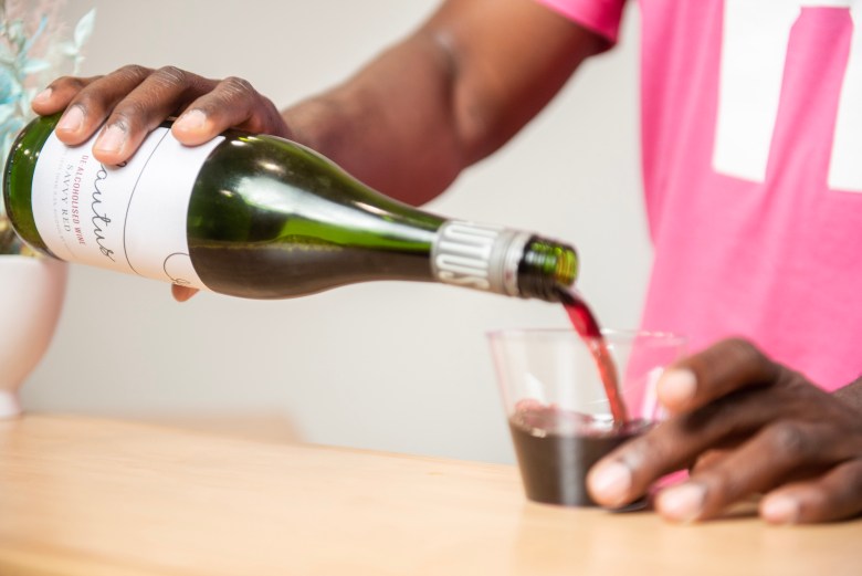 A photograph of a man pouring wine into a cup. 