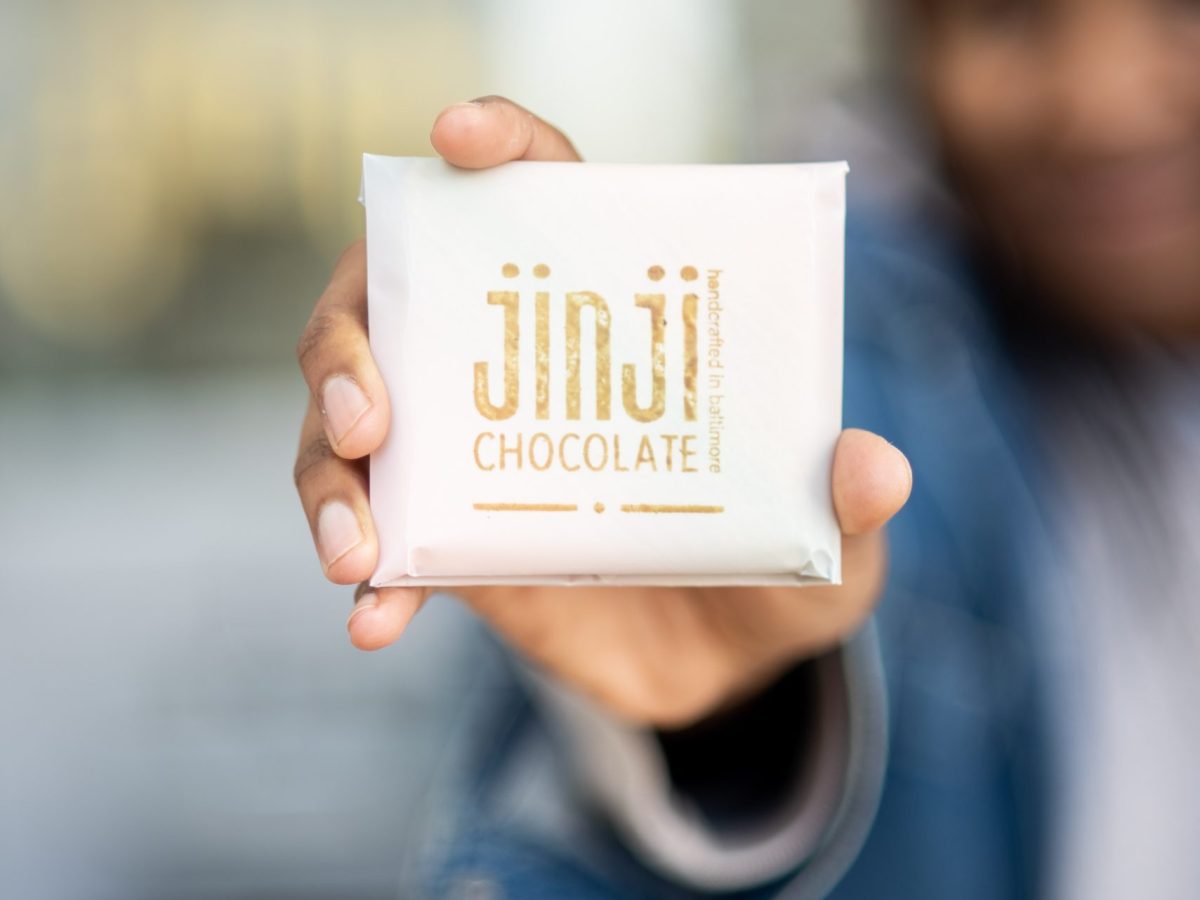 A bar of chocolate is held out of focus.