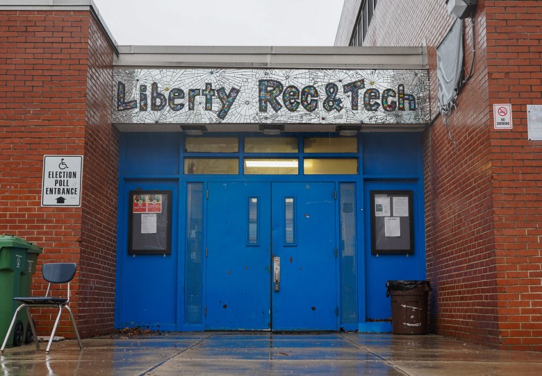 A photo of a brick building with a bright blue door. Above the entrance is a sign that reads: "Liberty Rec & Tech"