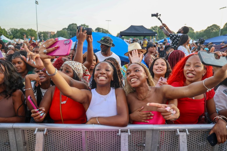 A crowd of people smiling and posing for photos. Some hold out their arms to take cell phone pictures.