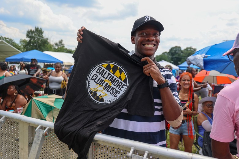 A smiling person holds up a t-shirt.