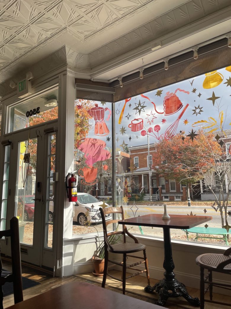 A photo of the inside of Arcola Cafe. The viewer can see tables and chairs and the view outside a large window