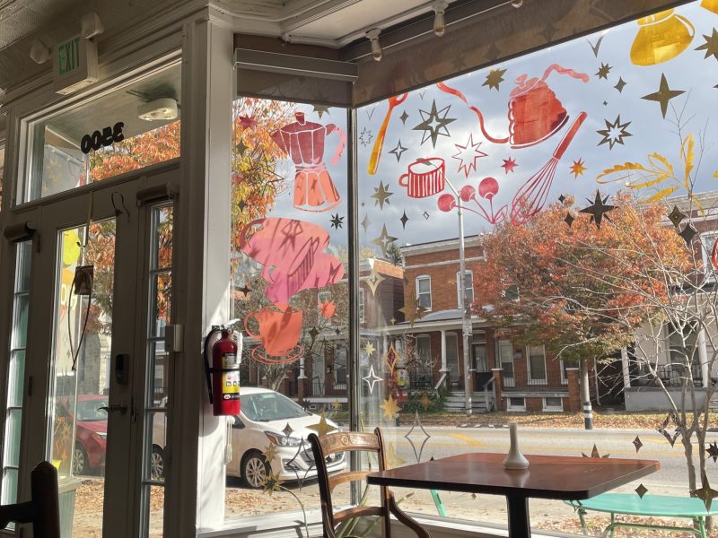 A photo of the inside of Arcola Cafe. The viewer can see tables and chairs and the view outside a large window