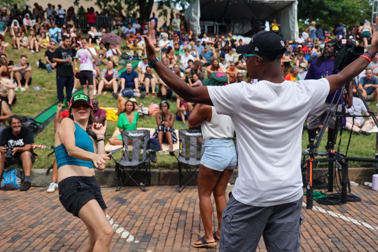 This picture shows various people dancing and having fun. A large crowd is in the background.