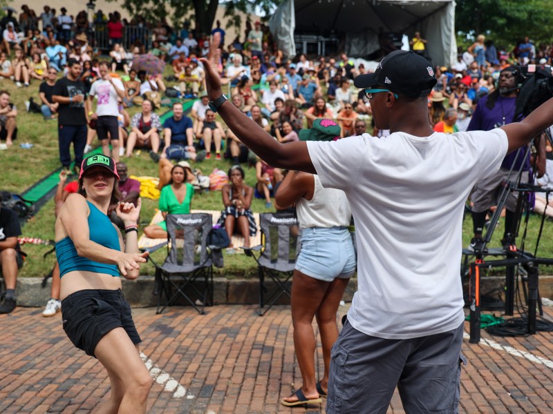 This picture shows various people dancing and having fun. A large crowd is in the background.