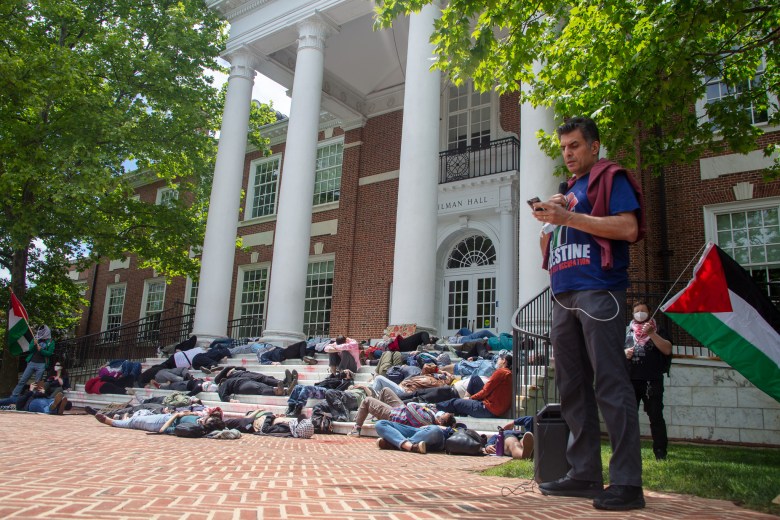 A person reads from their phone as the die-in happens behind them.