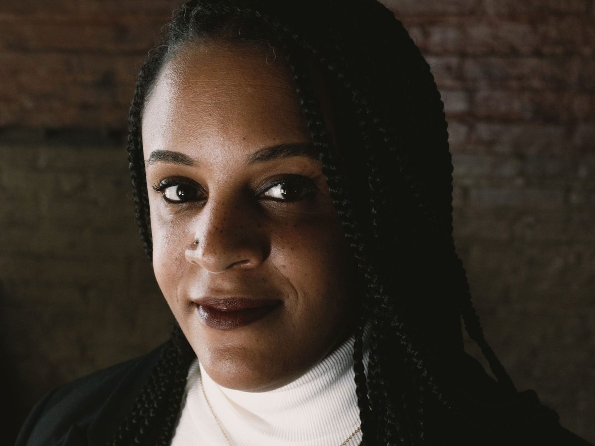 Photo of Baltimore Beat Editor-in-Chief Lisa Snowden. She is a Black woman with braids. She wears a white turtleneck top and a black blazer