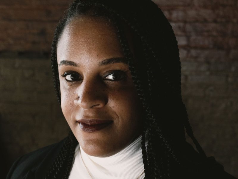Photo of Baltimore Beat Editor-in-Chief Lisa Snowden. She is a Black woman with braids. She wears a white turtleneck top and a black blazer