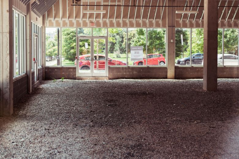 An unfinished gravel floor in the Center/West apartments with cars along North Schroeder Street in the background.