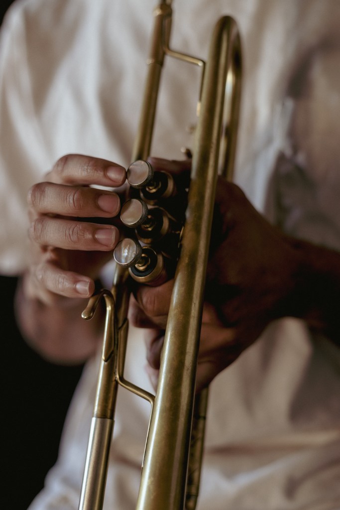 A photograph of a pair of hands holding a brass trumpet. 