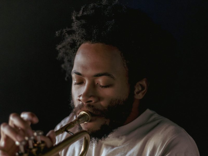 Photograph of a man with brown skin playing a trumpet