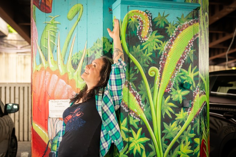 Bridget Cimino leans against a pillar she painted with carnivorous plants that are native to Maryland.