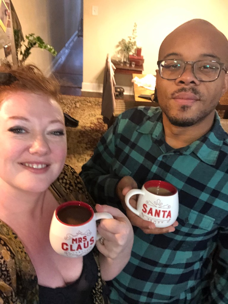 A couple poses for a holiday photo with matching holiday mugs. 