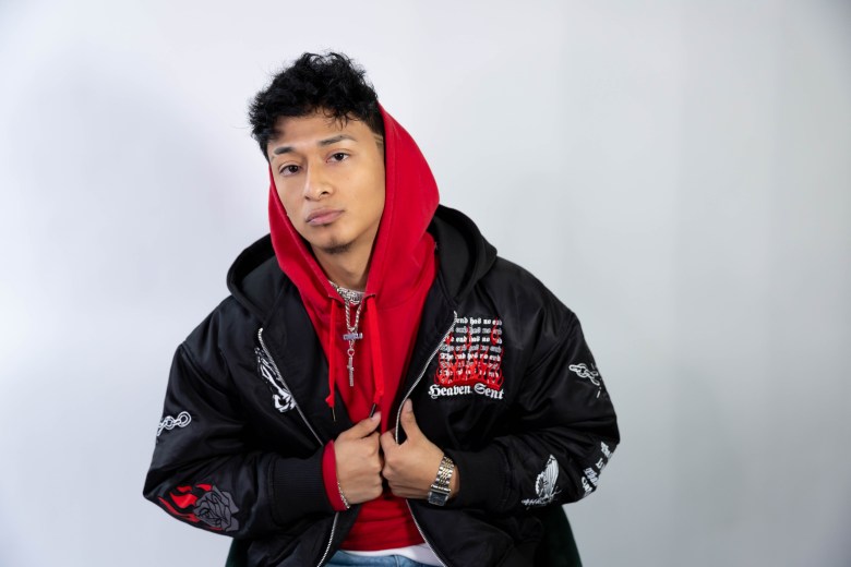 A photo of a person wearing a red hoodie underneath a black jacket.