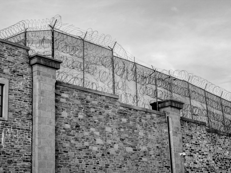 A photo of a wall topped with fencing and barbed wire.