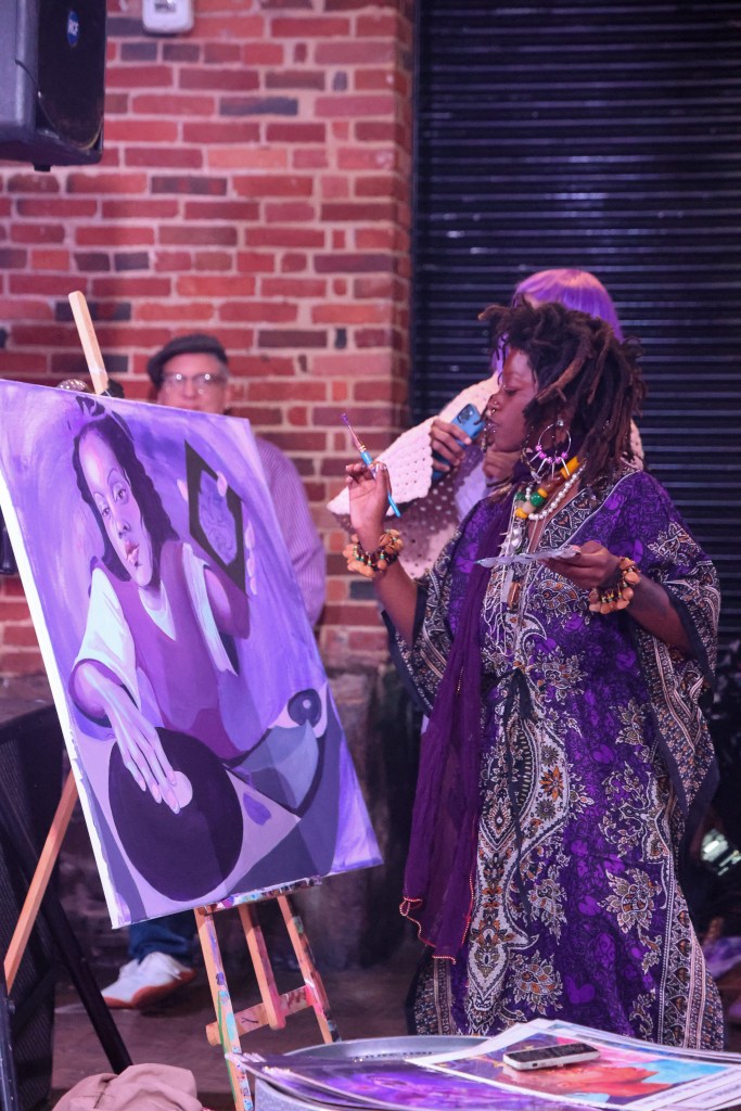 Photo of a person painting a work of art at public celebration. 