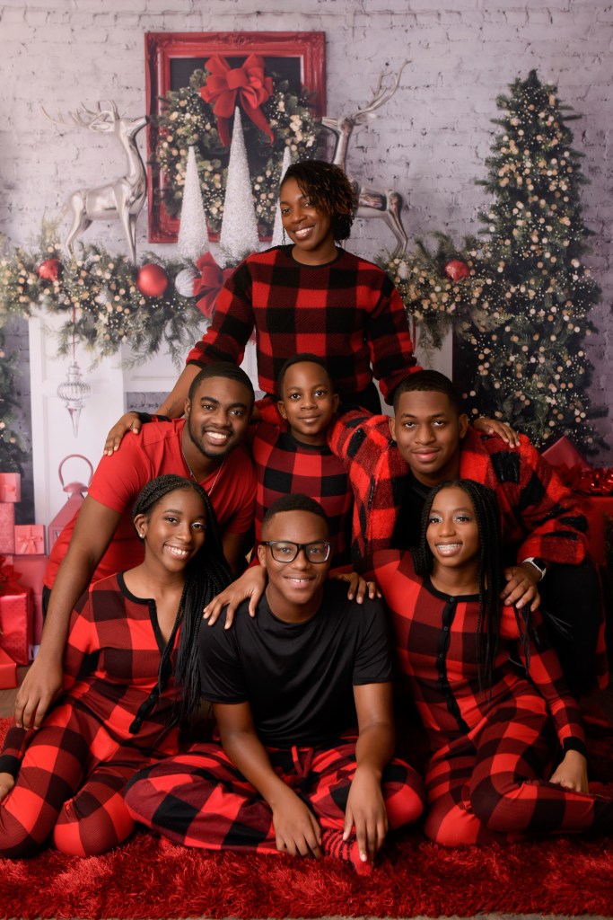 Seven family members pose for a holiday photo. They are wearing matching red holiday pajamas. 