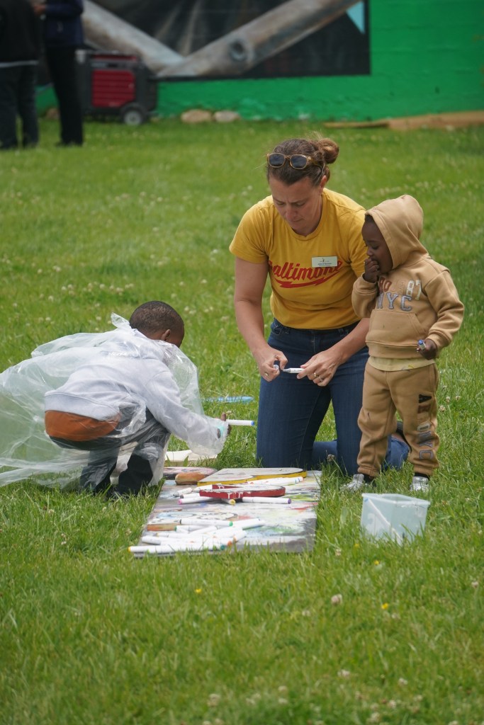 A woman kneels in the grass with two children.