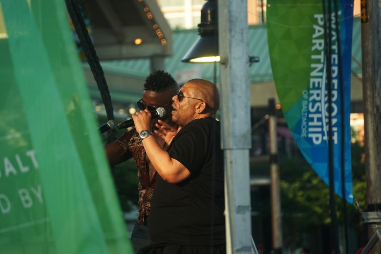 Two people hold microphones and address a crowd