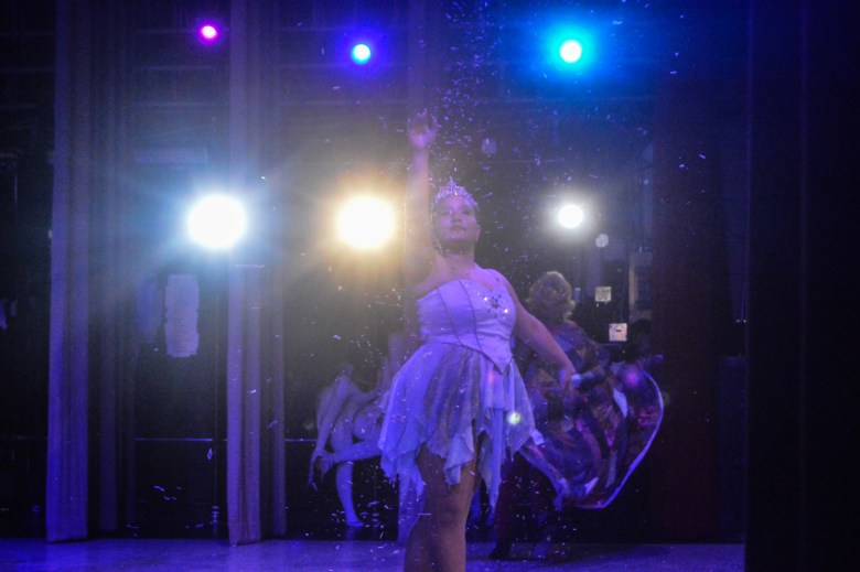 A dancer strikes a pose as snow falls on stage.