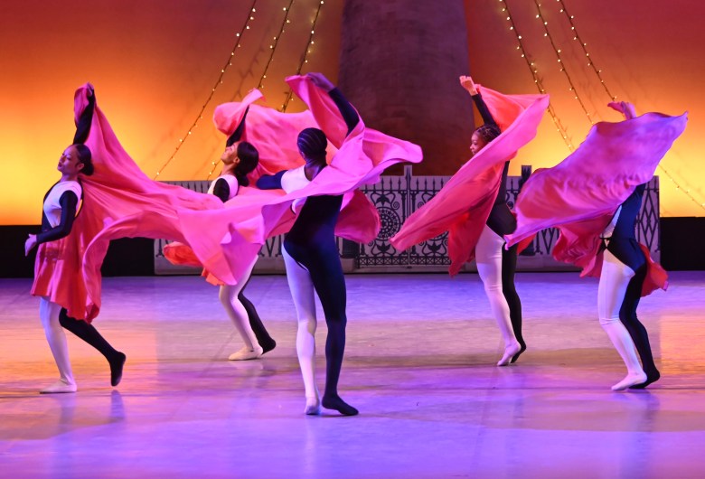 Dancers on stage dressed in black, white, and red.