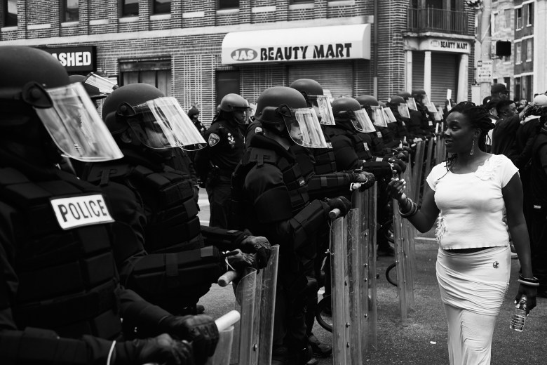 A woman dressed in white walks past a line of police officers.