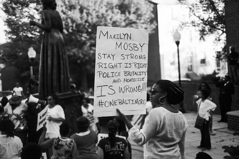 A woman holds a sign that reads: "Marily Mosby stay strong right is right police brutality and homicide is wrong!!! #onebaltimore"