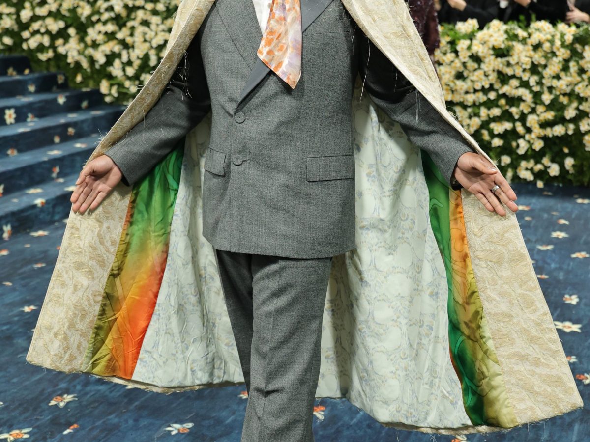A person with brown skin arrives at the 2025 Met Gala wearing a cape.