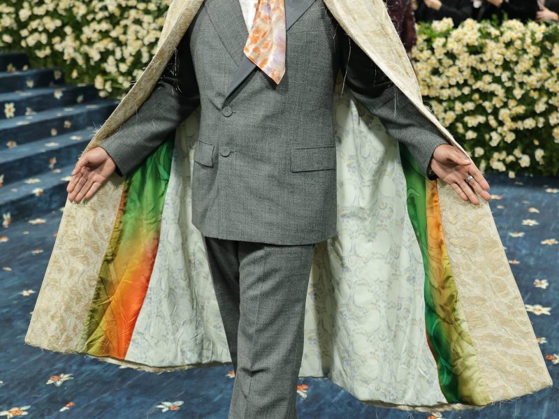 A person with brown skin arrives at the 2025 Met Gala wearing a cape.