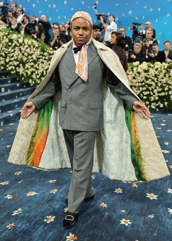 A person with brown skin arrives at the 2025 Met Gala wearing a cape.