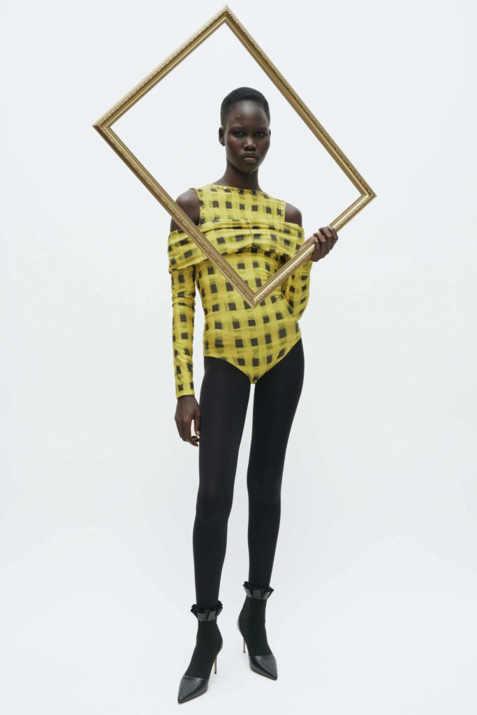 A model stands with a gilded frame.