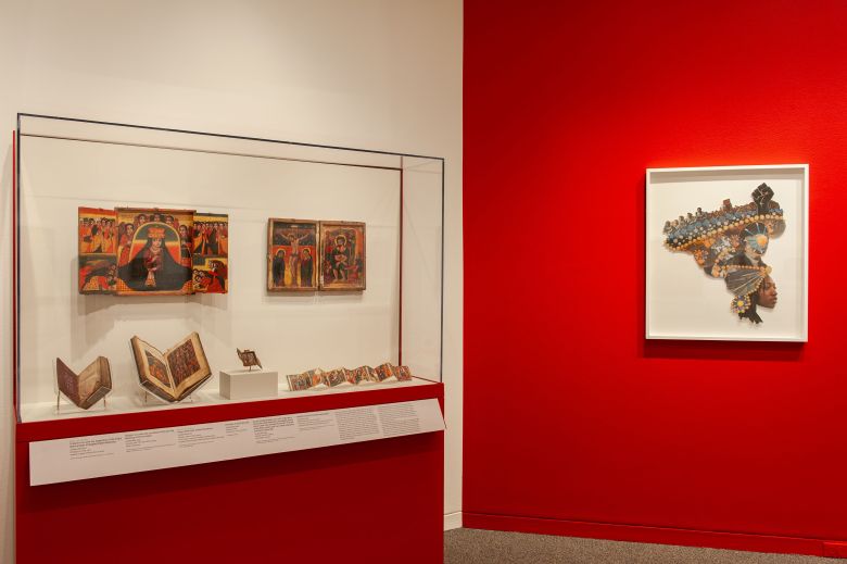 Artwork on view at the Walters against a red painted wall.