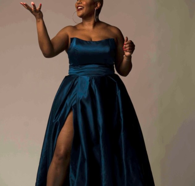 A woman wearing a blue dress tosses a football into the air.