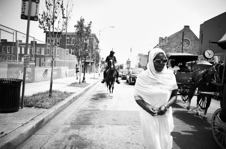 A woman dressed in all white walks beside the funeral procession.