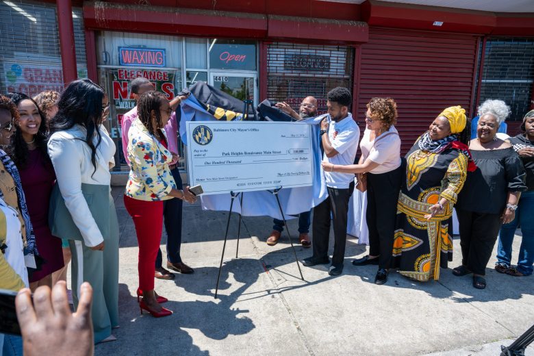 Baltimore Mayor Brandon Scott stands with other people around a large check.